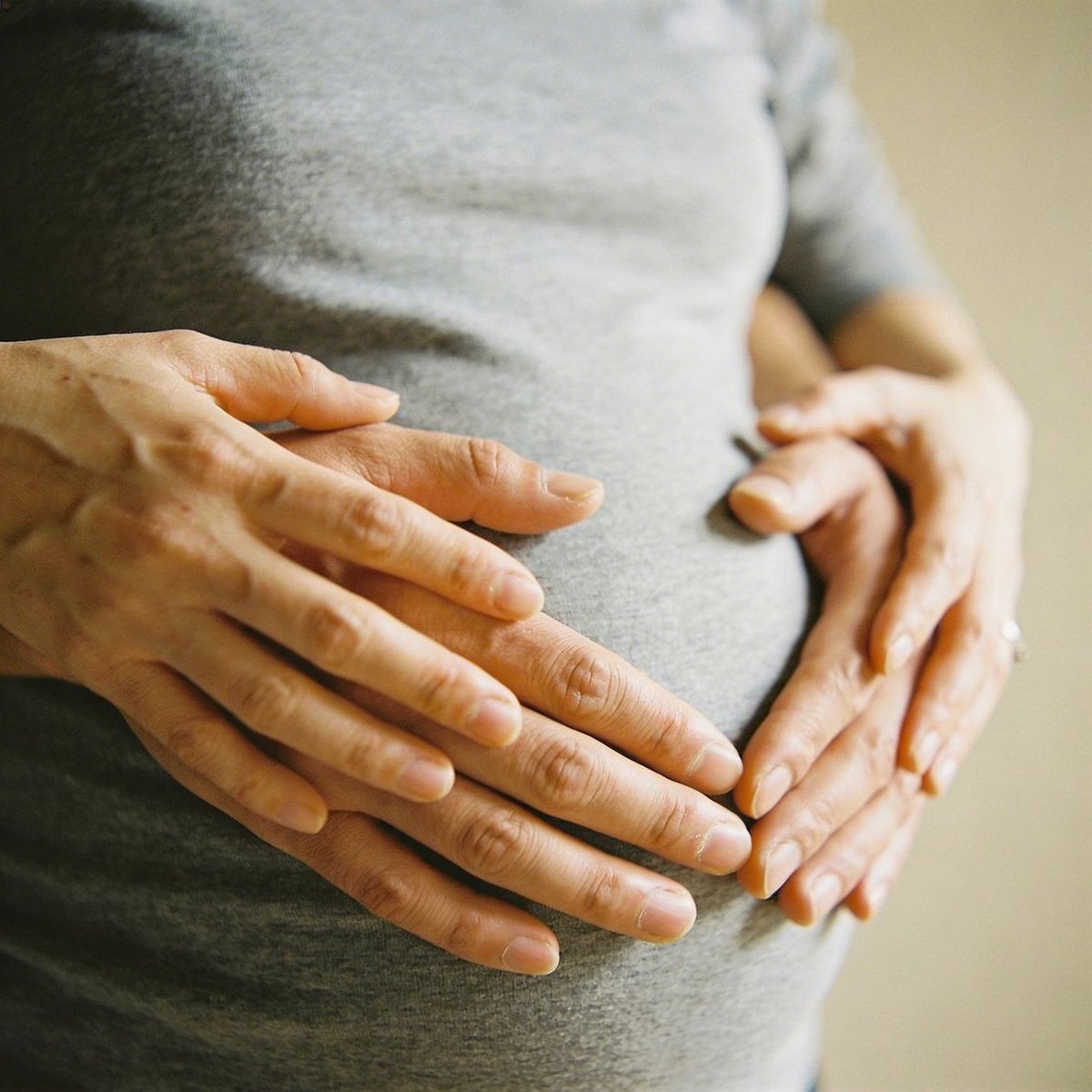 Kädet sydämen muodossa raskaana olevan naisen vatsalla